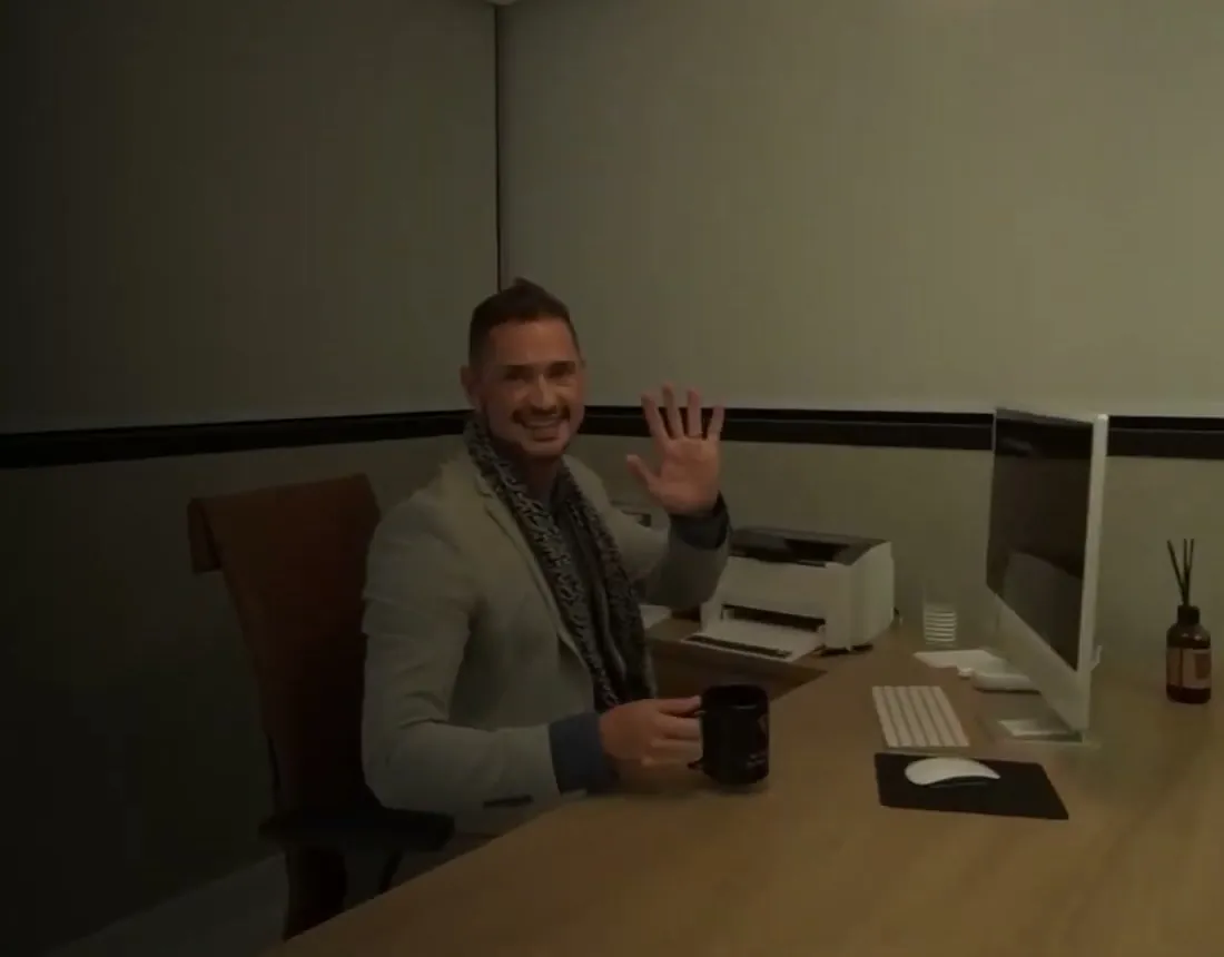Dr. Sharbo Casagrande acena e sorri, sentado à mesa do consultório do Instituto ISC, com uma caneca na mão