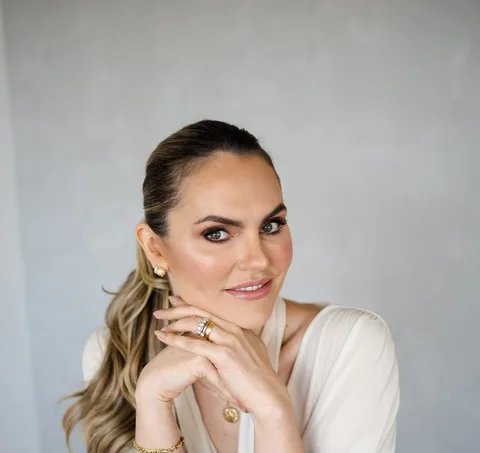 Dra. Amarilis Tais Sand, de roupa bege, junto a uma janela